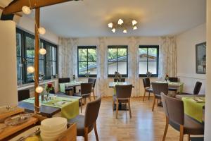 un restaurante con mesas, sillas y ventanas en Landhotel Villa Moritz garni, en Oberahr