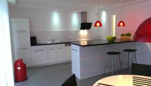 Una cocina con gabinetes blancos y una encimera con taburetes. en dat witte hus 1, en Büsum