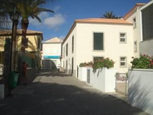 an empty street with a white building and palm trees at Villa Pitta in Vila Baleira +6 photos