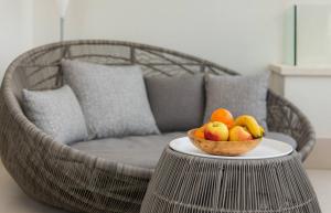 a wicker chair with a bowl of fruit on a table at Alba Residence in Split