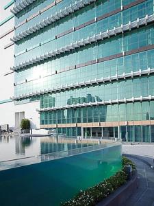 a large glass building with a swimming pool in front of it at S31 Sukhumvit Hotel in Bangkok