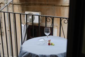 una mesa con una copa de vino y flores en ella en Casa Rubino, en Cefalú