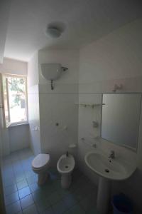 a white bathroom with a toilet and a sink at Appartamenti Villa Monticelli in Marina di Campo