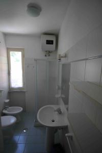 a white bathroom with a sink and a toilet at Appartamenti Villa Monticelli in Marina di Campo