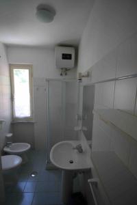 uma casa de banho branca com um lavatório e um WC em Appartamenti Villa Monticelli em Marina di Campo