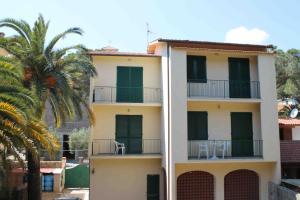 um edifício com uma palmeira em frente em Appartamenti Villa Monticelli em Marina di Campo