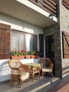 eine Terrasse mit Korbstühlen, einem Tisch und einem Fenster in der Unterkunft Agropensiunea Ioana in Suceava
