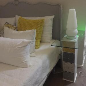 Una cama con almohadas blancas y una lámpara en una mesa lateral. en Agriturismo LaTerzola 3.0, en Fiorenzuola dʼArda