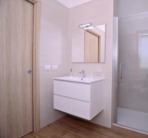 a white bathroom with a sink and a mirror at Altomare Case Vacanza in Porto Cesareo