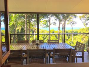 a wooden table with chairs and a large window at Daintree Magic Holiday House in Cow Bay