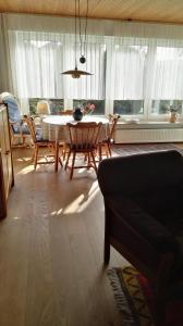 Una sala de estar con mesa y sillas y ventanas. en Haus Antje, en Norddeich