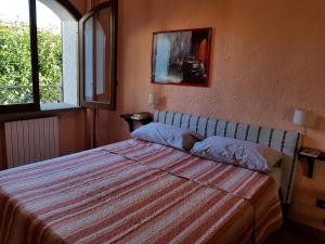 a bedroom with a bed with a striped bedspread and two windows at La Limonaia in Castel Volturno