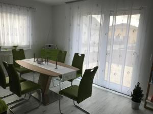 a dining room with a table and green chairs at Haus Seewind Hohenfelden in Hohenfelden