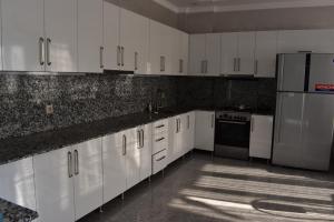 una cucina con armadietti bianchi ed elettrodomestici in acciaio inossidabile di Guest house BAGRATIONI a Kobuleti