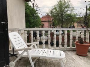 a white chair sitting on a porch next to a fence at Mosaico Alfetta Hostel in Timişoara