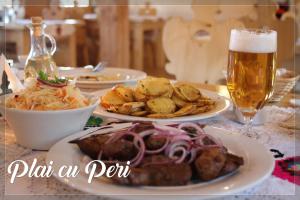 a table with plates of food and a glass of beer at "Plai cu Peri" in Săpânța