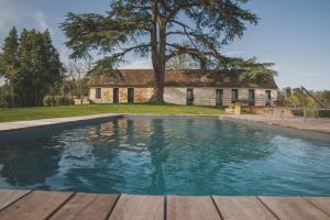 uma piscina em frente a uma casa com uma árvore em Villa Korum em Bergerac