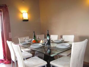 ローレにあるVilla Tiagoのダイニングルーム(白い椅子とワインボトル付きのテーブル付)