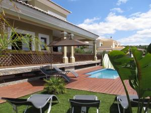 een achtertuin met een zwembad en stoelen en een huis bij Villa Tiago in Loulé