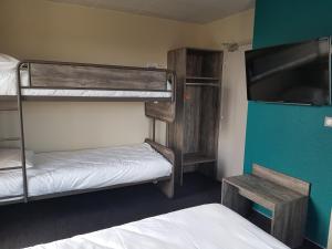 a room with two bunk beds and a flat screen tv at Hôtel Jeanne D'Arc in Saint-Chély-dʼApcher