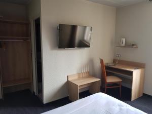 サン・シェリー・ダプシェにあるオテル ジャンヌ ダルクのデスク、壁掛けテレビが備わるホテルルームです。