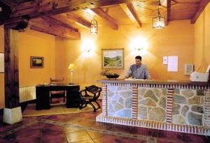 a man standing behind a bar in a restaurant at Hotel El Castrejon in Cebreros