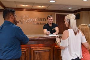 a group of people standing around a reception counter at New Victorian Inn & Suites Omaha in Omaha