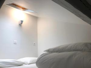 a white bedroom with a bed and a light on the wall at L'IDEAL 9 (hypercentre avec terrasse) in Deauville
