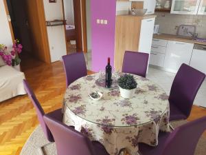 una mesa con sillas moradas y una botella de vino en Apartments Ivona, en Trogir