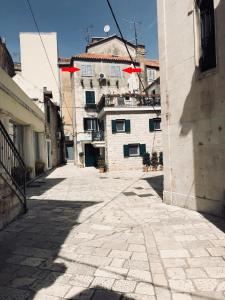 un callejón con un edificio de fondo con sombrillas rojas en Apartment Ante - Diocletian's palace, en Split