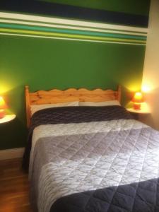 um quarto com uma cama com uma parede verde em Naomh Colman B&B em Gort