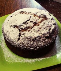un gâteau au chocolat avec du sucre en poudre sur une assiette verte dans l'établissement Sa Mama e Su Sole, à Alghero