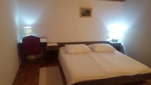 a bedroom with a bed and a desk with two lights at Begovi Dvori in Rab