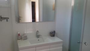 a white bathroom with a sink and a mirror at A Place To Remember in Ma‘alot