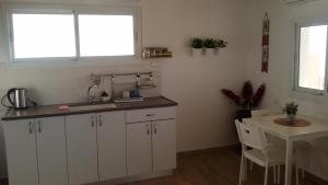 a kitchen with white cabinets and a table and window at A Place To Remember in Ma‘alot +15 photos