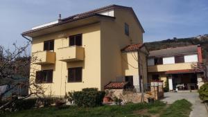 a large yellow house with a hill in the background at Begovi Dvori in Rab