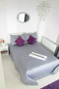 a bedroom with a bed with purple pillows and a mirror at White Luxury Apartment in Sibiu