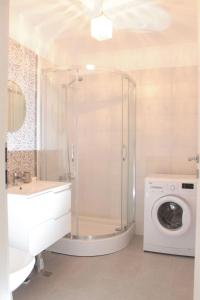 a bathroom with a shower and a washing machine at White Luxury Apartment in Sibiu +27 photos