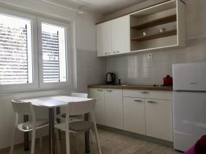 cocina con armarios blancos, mesa y sillas en Seaside Apartments, en Makarska