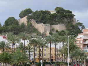 a castle on top of a hill with palm trees at Pl Les Bovetes Apt in Denia +15 photos