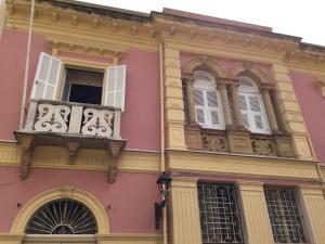 Edificio rosa con balcón y ventanas en Casa Tonina, en Carloforte