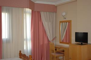 a hotel room with a bed and a desk and a television at Hotel Costa Verde in Villadesuso