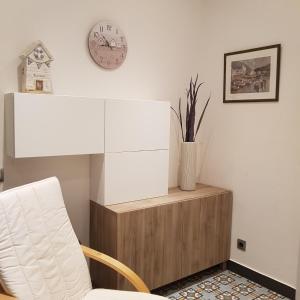 a room with a white chair and a clock on the wall at Apartamentos Nouvilas in Portbou