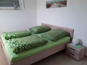 a bed with green sheets and pillows on it at Haus am Leuchtfeuer in Peenemünde