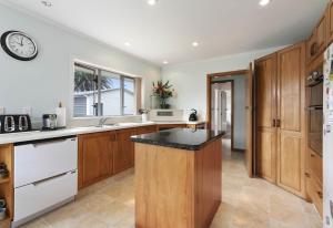 a kitchen with wooden cabinets and a black counter top at Auckland Airport Guest House in Auckland