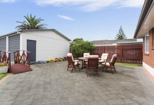 a patio with a table and chairs and a fence at Auckland Airport Guest House in Auckland