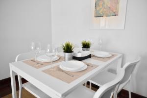 a white dining table with white plates and wine glasses at Plaza Pio XII in San Sebastián