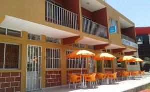 a row of orange chairs and umbrellas in front of a building at Pensão Asa Branca in Assomada