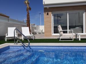 a pool with two chairs and a palm tree at Villa Pinatar in San Pedro del Pinatar
