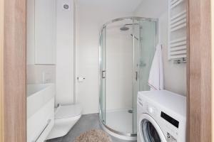 a bathroom with a shower and a washing machine at Raval Apartments - Fresh Turquoise in Rewal